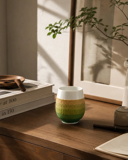 A handwoven bamboo porcelain tea cup placed in a calm study setting, designed for quiet rituals and slow living spaces.