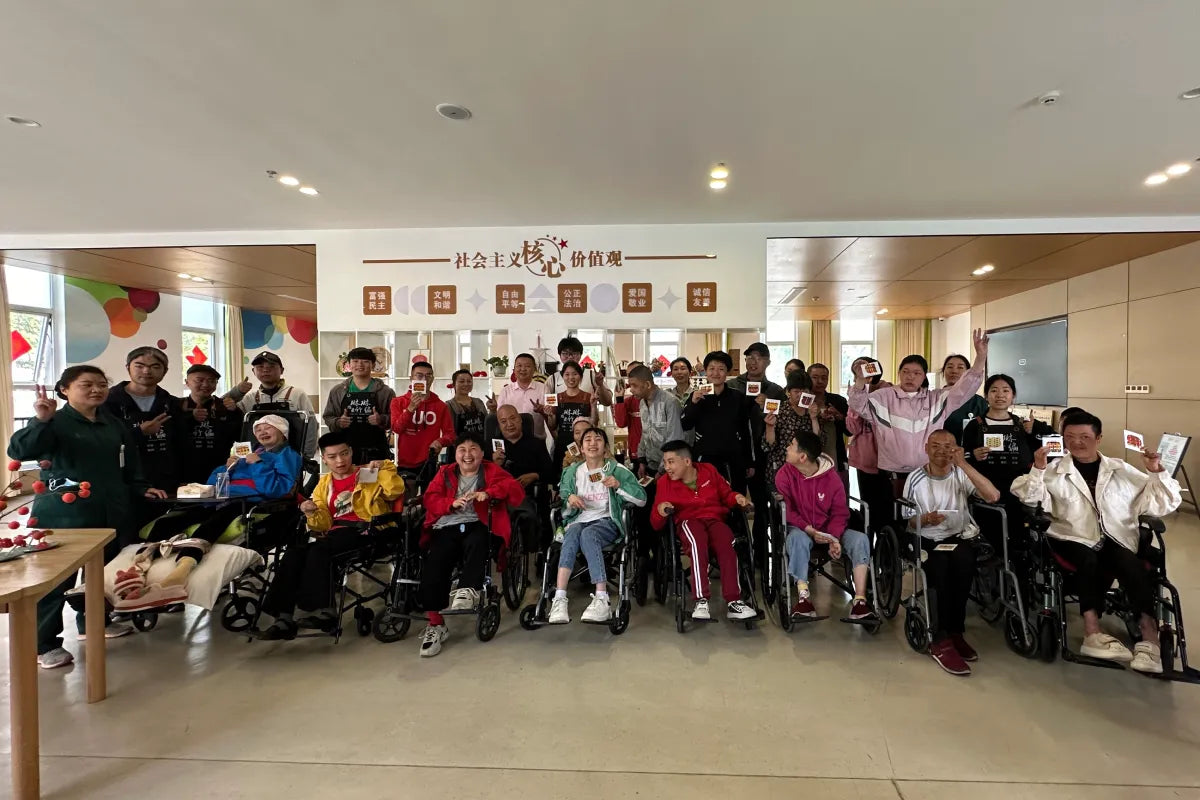 Liu Luolin and participants displaying completed bamboo-weaving pieces after a community workshop for people with disabilities.