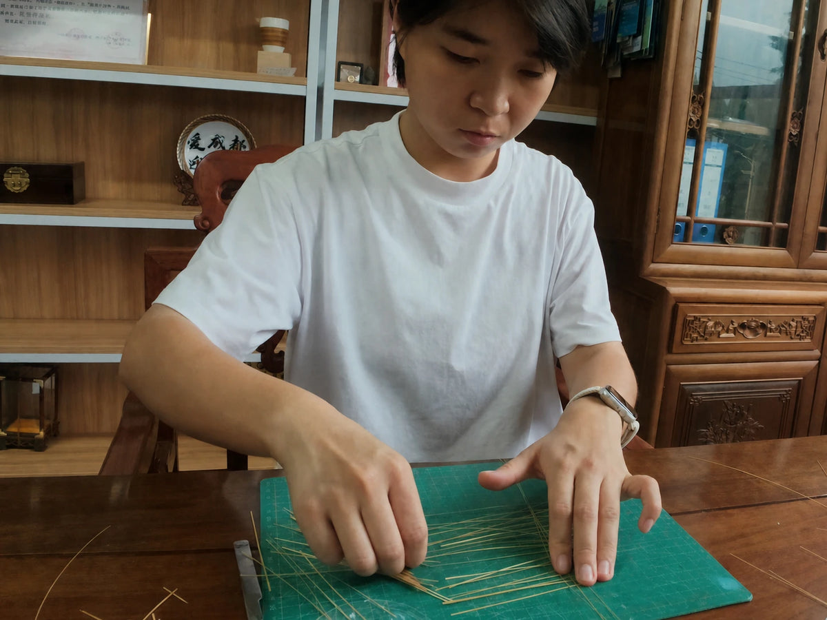 Liu Luolin sorting and aligning fine bamboo filaments before weaving