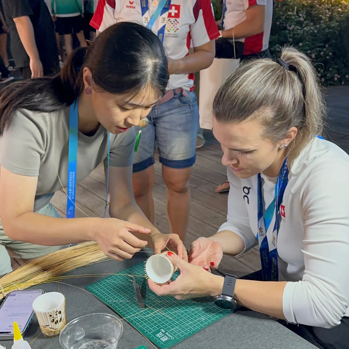 A participant learning to weave bamboo around a porcelain cup with guidance from an artisan.