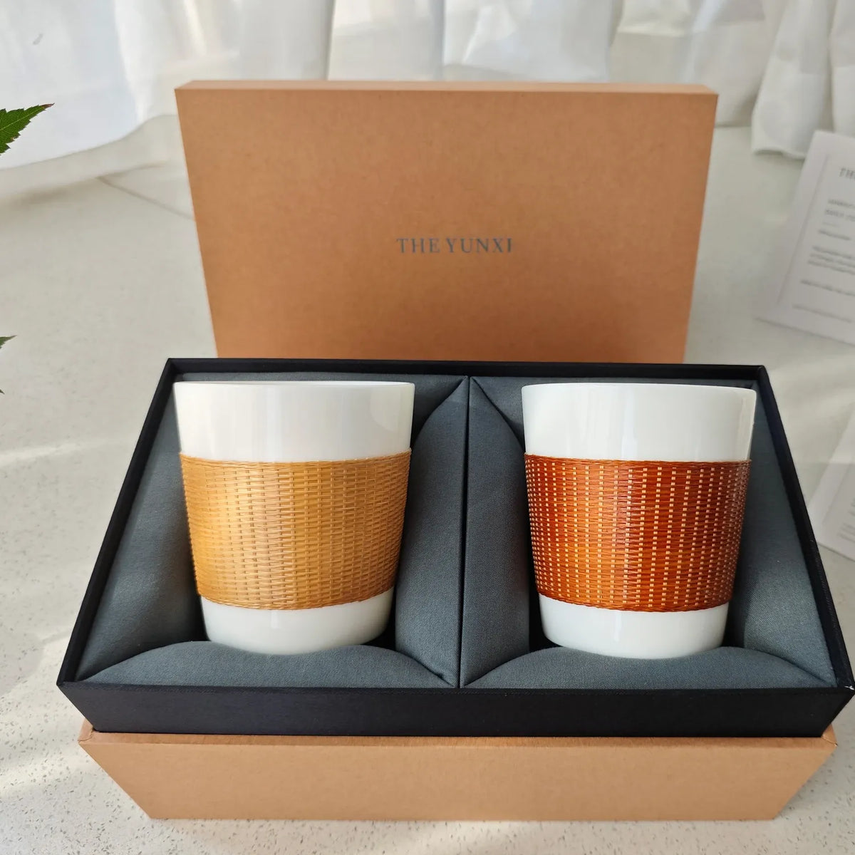 Natural and Baked Bamboo over Porcelain Daily Cups in an open THE YUNXI gift box with craft and care cards.