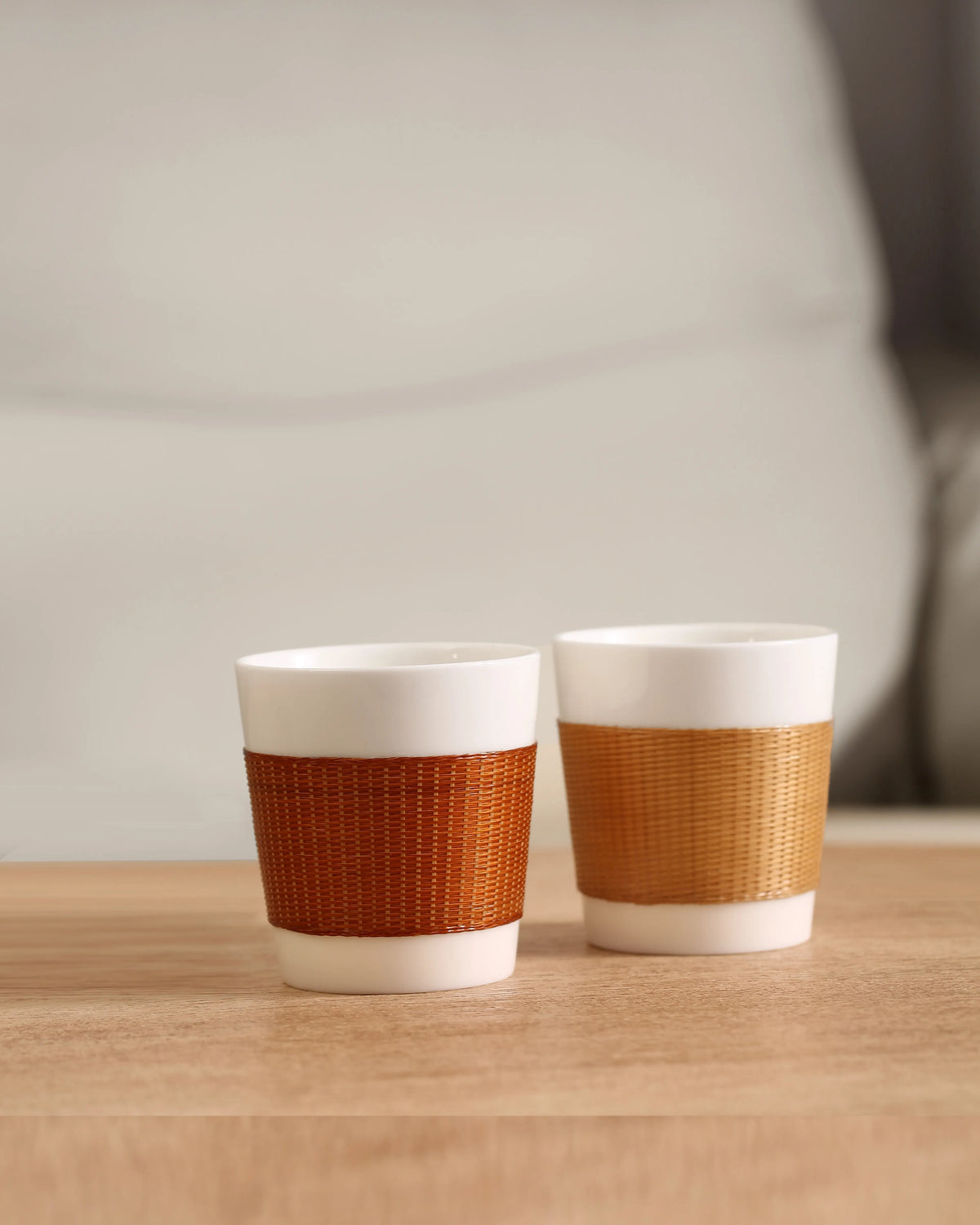 THE YUNXI Daily Cup in Baked and Natural, featuring woven bamboo sleeves over white porcelain.