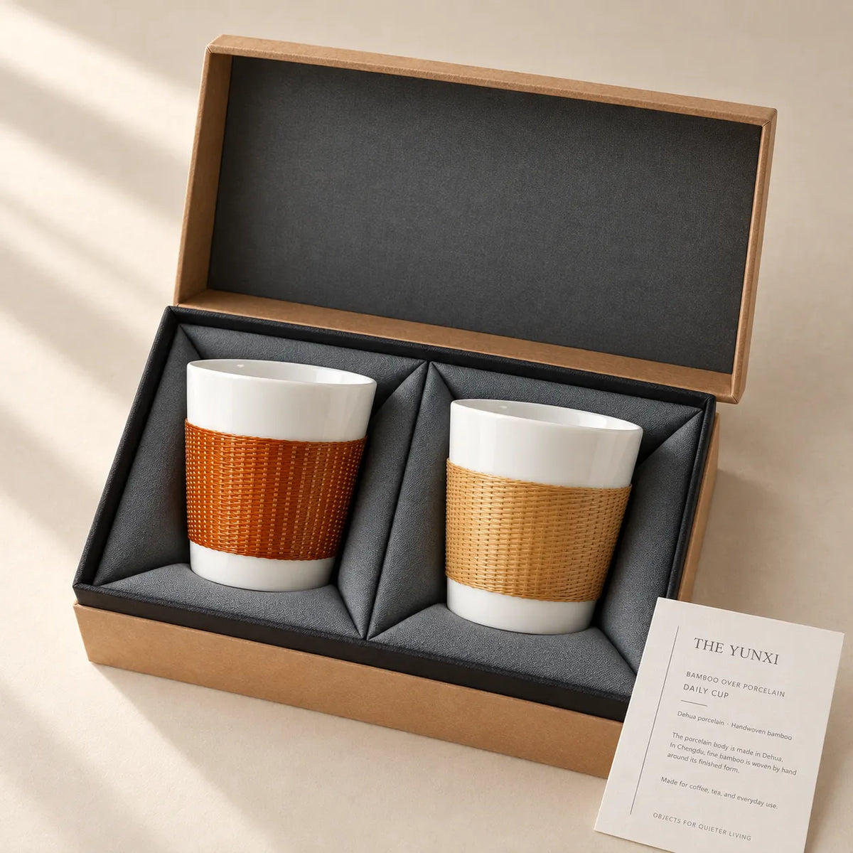 THE YUNXI Daily Cup duo in Baked and Natural bamboo finishes, in an open kraft gift box with charcoal lining and a craft card.