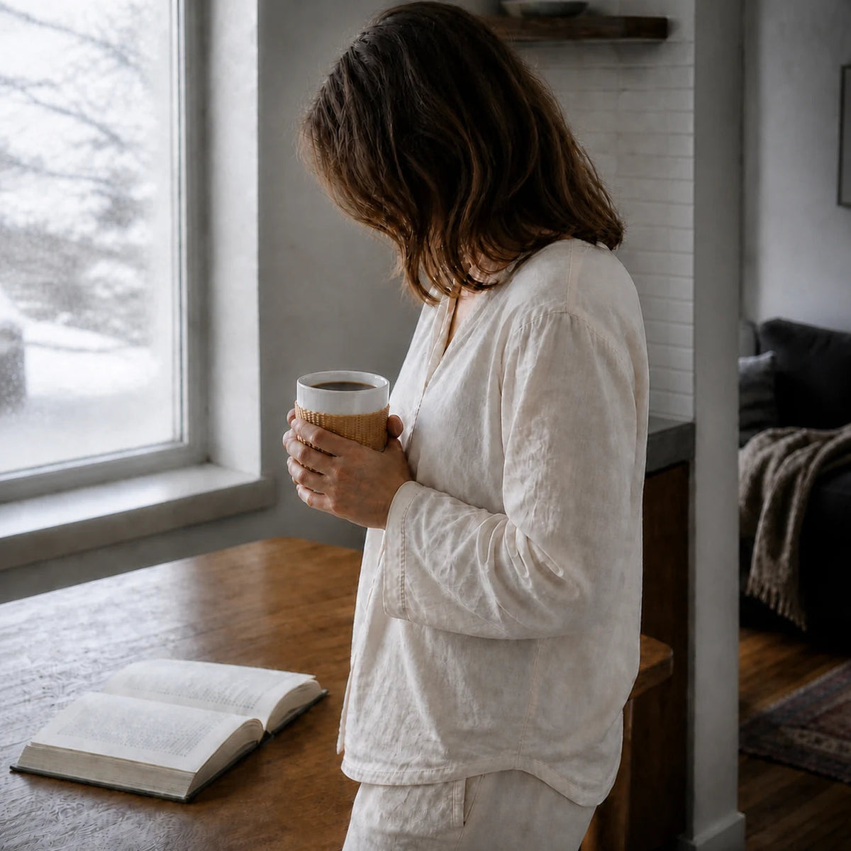 Woman holding a Bamboo over Porcelain cup beside a winter window